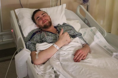 Patient gives a thumbs-up from his hospital bed after an awake craniotomy.